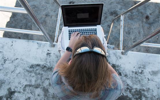 Top down view of  Christopher  typing on his laptop from the lifeguard tower.