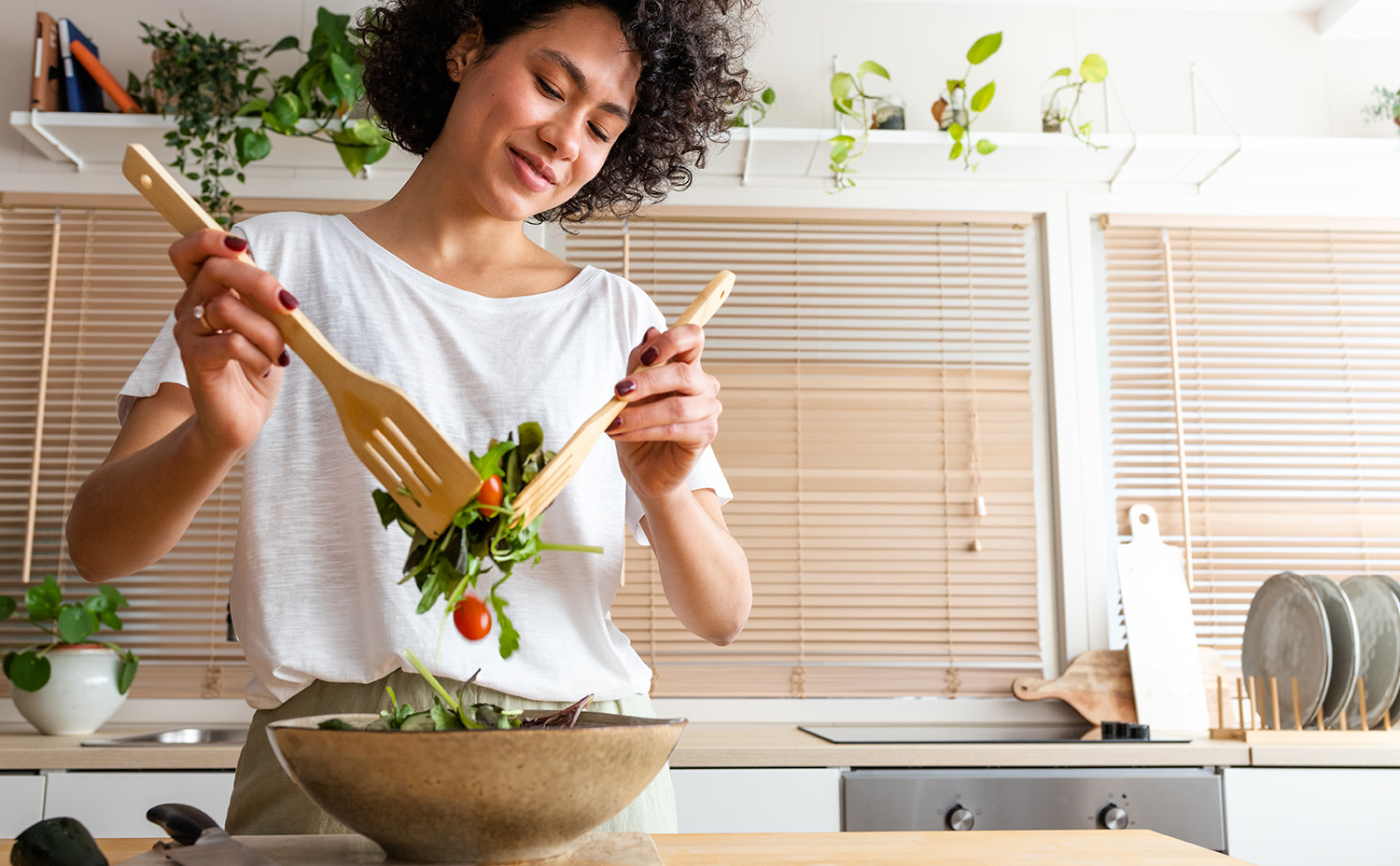 A woman preparing a healthy salad in a bowl.