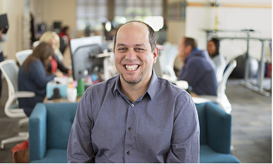 Manny Hernandez, in an office setting, smiling.